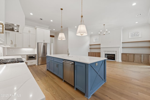 kitchen featuring blue cabinets, sink, white cabinetry, decorative light fixtures, and appliances with stainless steel finishes