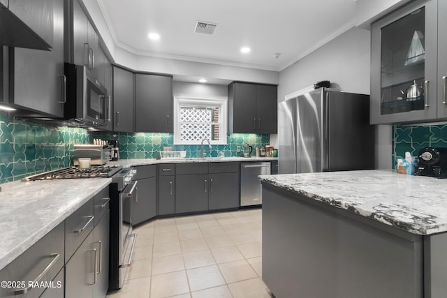 kitchen featuring sink, tasteful backsplash, light tile patterned floors, ornamental molding, and appliances with stainless steel finishes