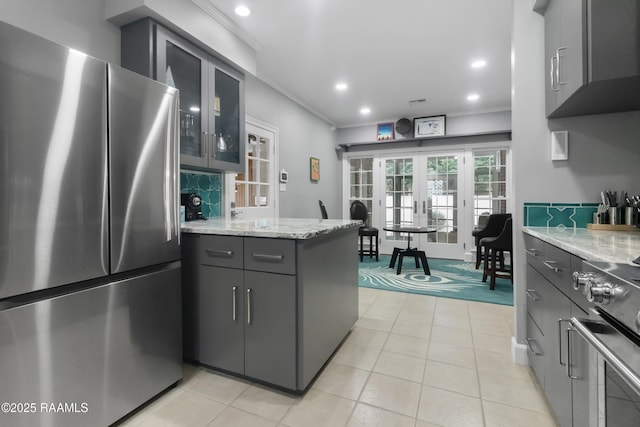 kitchen with french doors, gray cabinetry, kitchen peninsula, stainless steel appliances, and light stone countertops