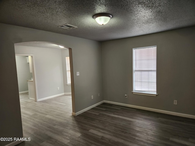 unfurnished room with dark hardwood / wood-style floors and a textured ceiling