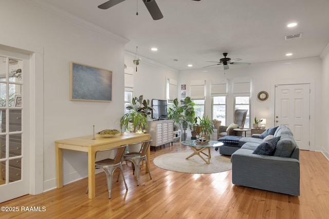 living room featuring crown molding, ceiling fan, and light hardwood / wood-style flooring