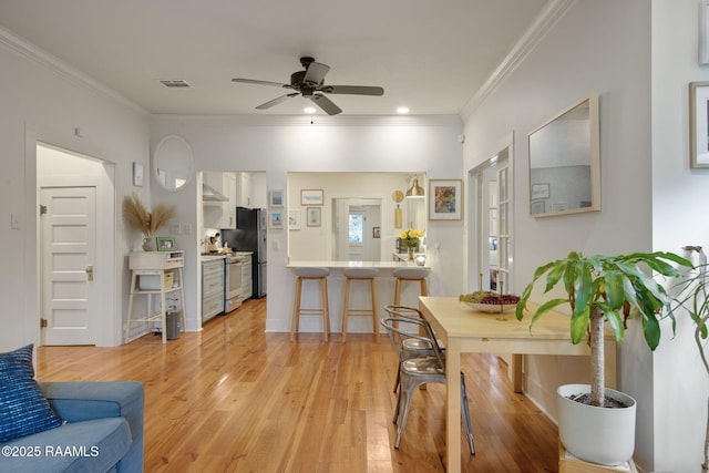 dining room with ornamental molding, ceiling fan, and light wood-type flooring