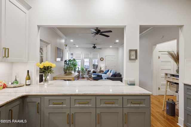 kitchen featuring crown molding, gray cabinetry, and light stone counters