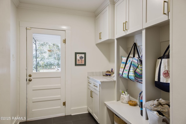 mudroom with dark tile patterned floors and ornamental molding