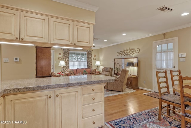 kitchen featuring light stone countertops, crown molding, cream cabinets, and light hardwood / wood-style floors