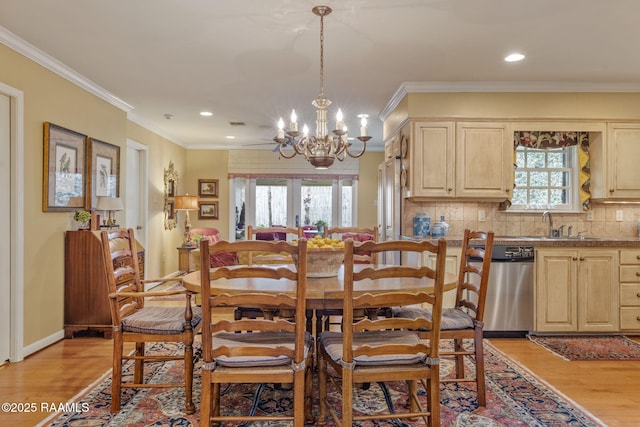 dining room featuring sink, light wood-type flooring, ornamental molding, an inviting chandelier, and french doors