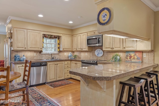 kitchen featuring stainless steel appliances, sink, a breakfast bar area, and kitchen peninsula