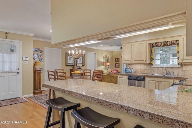 kitchen featuring sink, light hardwood / wood-style flooring, dishwasher, a kitchen bar, and decorative backsplash