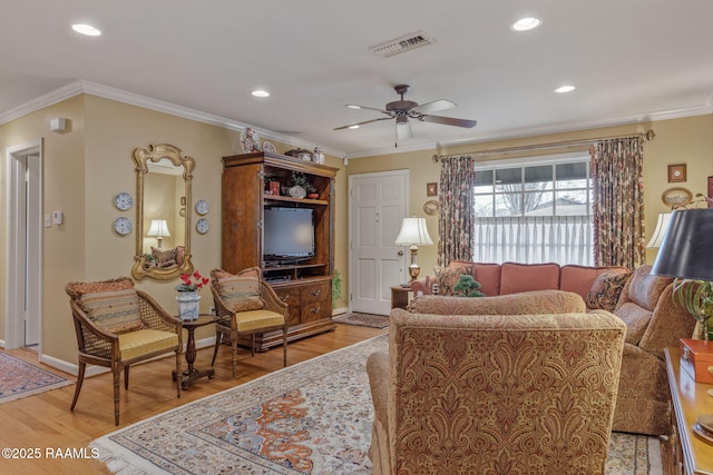 living room featuring ceiling fan, ornamental molding, and light wood-type flooring