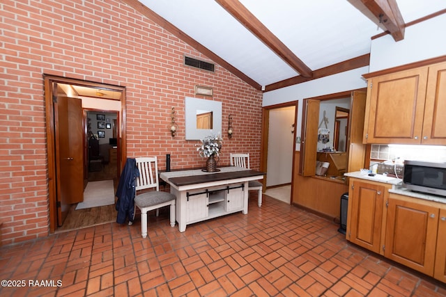 kitchen featuring high vaulted ceiling, beamed ceiling, and brick wall