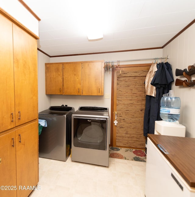 laundry room with crown molding, cabinets, and washing machine and clothes dryer