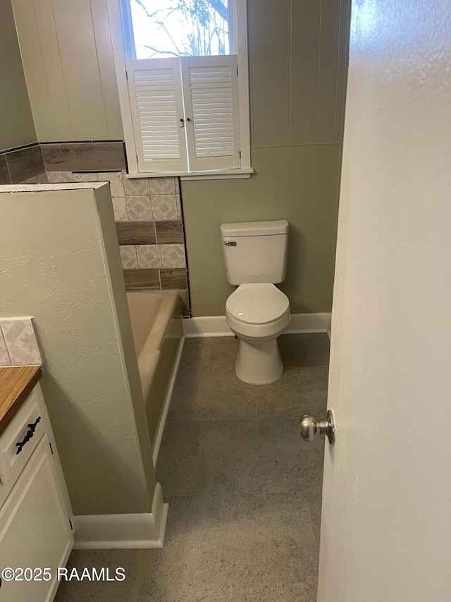 bathroom featuring a tub to relax in, toilet, and vanity