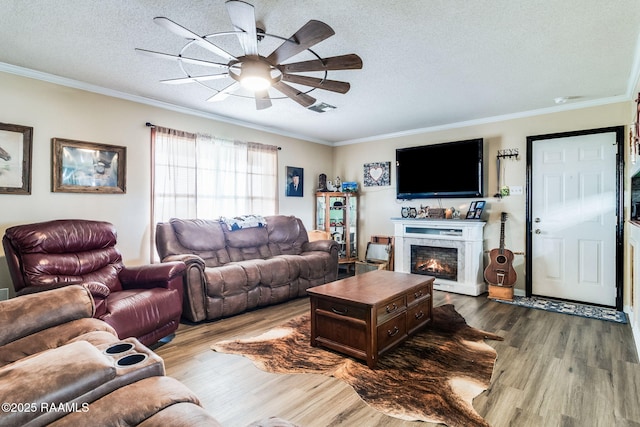 living room with hardwood / wood-style floors, ornamental molding, and a textured ceiling