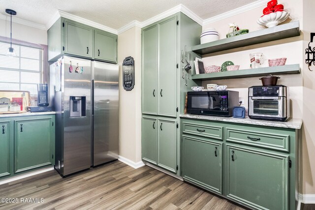 kitchen featuring crown molding, stainless steel fridge, dark wood-type flooring, green cabinets, and decorative light fixtures