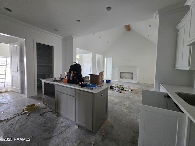 kitchen featuring white cabinets, open floor plan, a center island, light countertops, and crown molding