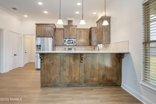 kitchen with appliances with stainless steel finishes, decorative light fixtures, plenty of natural light, and kitchen peninsula