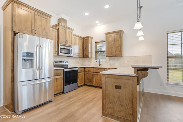 kitchen with pendant lighting, appliances with stainless steel finishes, kitchen peninsula, and decorative backsplash