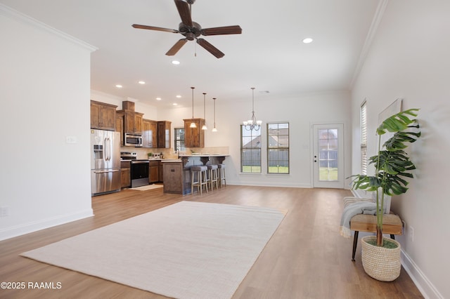 kitchen featuring crown molding, light wood-type flooring, a kitchen breakfast bar, pendant lighting, and stainless steel appliances