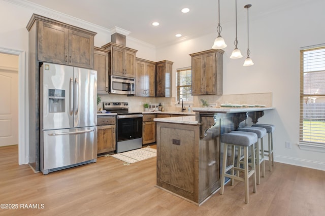 kitchen with appliances with stainless steel finishes, backsplash, a kitchen breakfast bar, decorative light fixtures, and kitchen peninsula