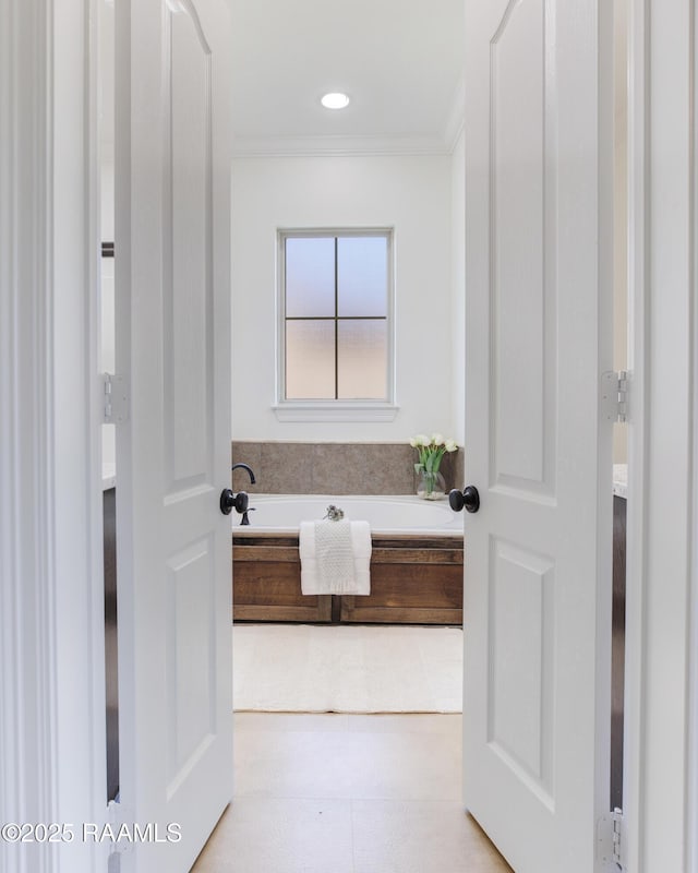 bathroom featuring ornamental molding and a bath