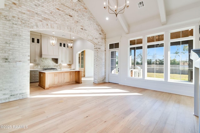 kitchen with high vaulted ceiling, decorative light fixtures, beamed ceiling, decorative backsplash, and a spacious island