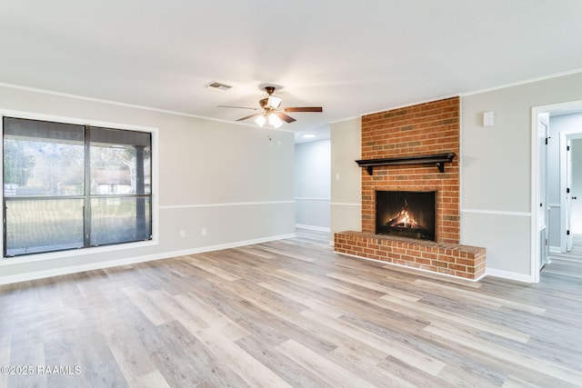 unfurnished living room featuring a brick fireplace, crown molding, light hardwood / wood-style floors, and ceiling fan