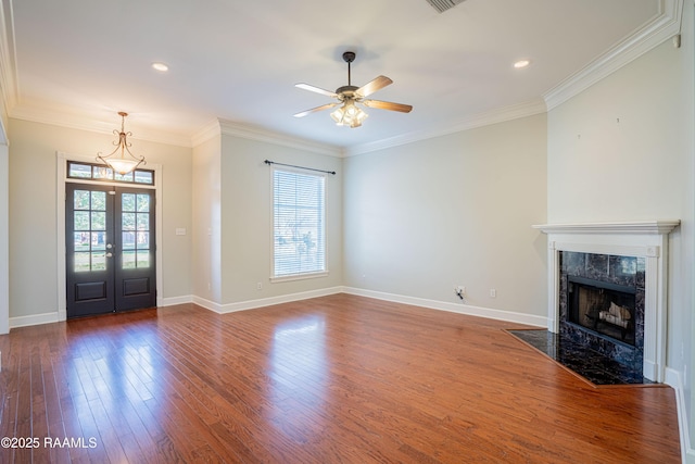 unfurnished living room featuring wood-type flooring, ceiling fan, a high end fireplace, crown molding, and french doors