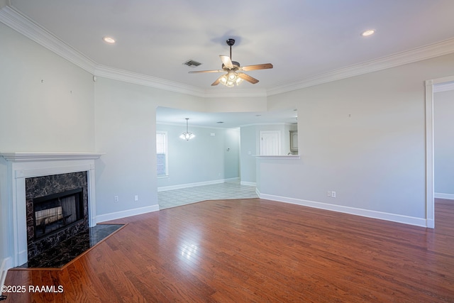 unfurnished living room featuring ceiling fan with notable chandelier, wood-type flooring, ornamental molding, and a premium fireplace