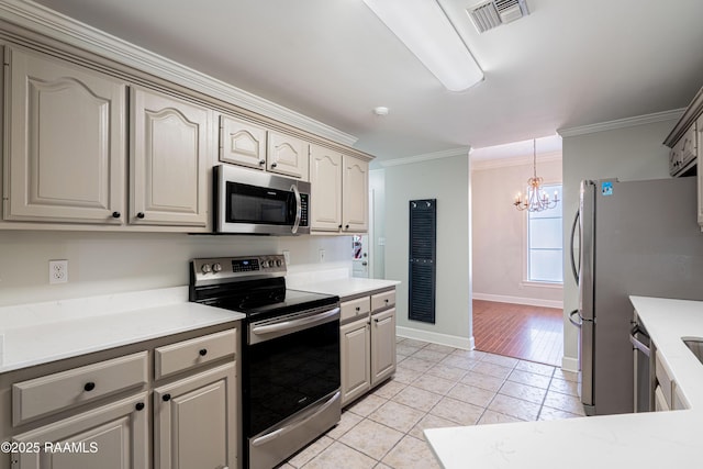 kitchen with light tile patterned floors, crown molding, a chandelier, and appliances with stainless steel finishes