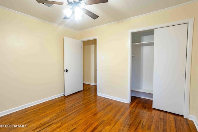 unfurnished bedroom with dark wood-type flooring, ornamental molding, a closet, and ceiling fan