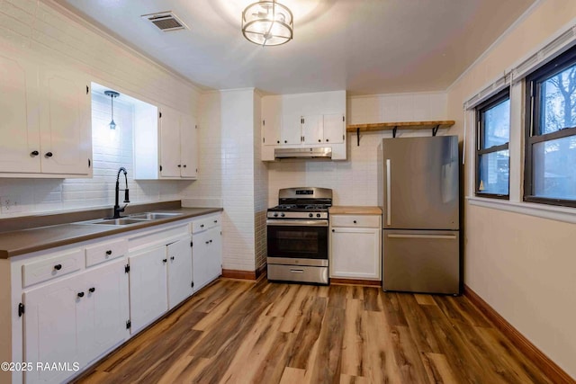 kitchen with sink, hardwood / wood-style floors, stainless steel appliances, tasteful backsplash, and white cabinets