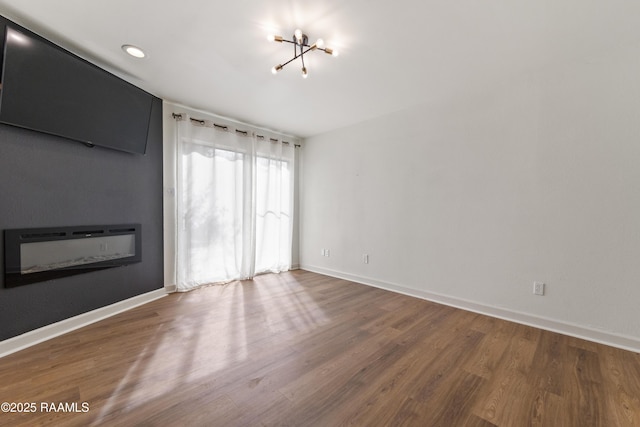 empty room with hardwood / wood-style flooring and a chandelier