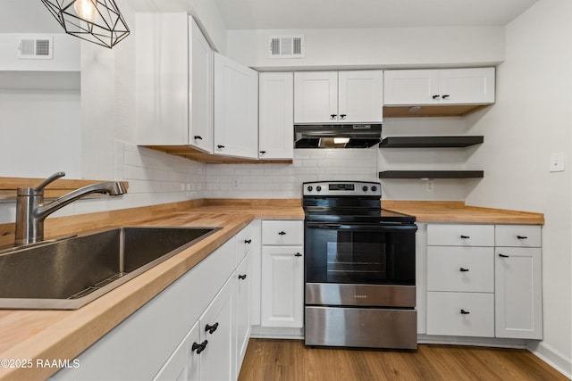 kitchen featuring wooden counters, stainless steel electric stove, sink, and white cabinets