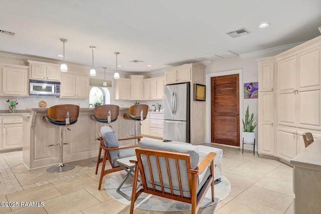 kitchen with ornamental molding, appliances with stainless steel finishes, a kitchen breakfast bar, pendant lighting, and light stone countertops