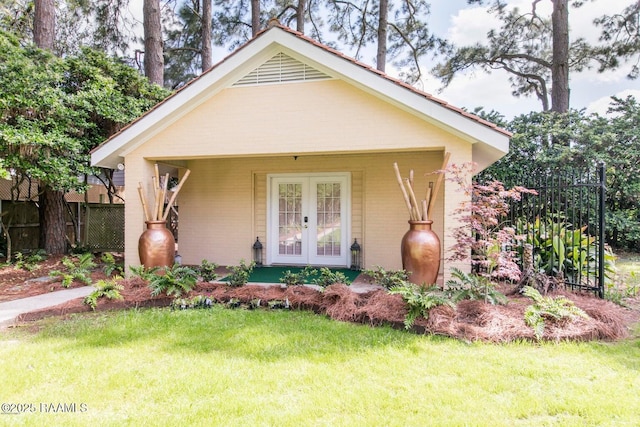 bungalow-style home with a front lawn and french doors