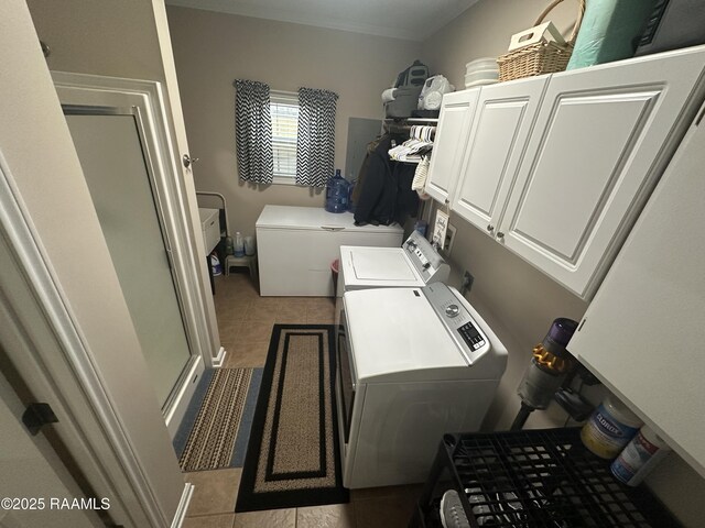 washroom with light tile patterned floors, ornamental molding, washing machine and dryer, and cabinets