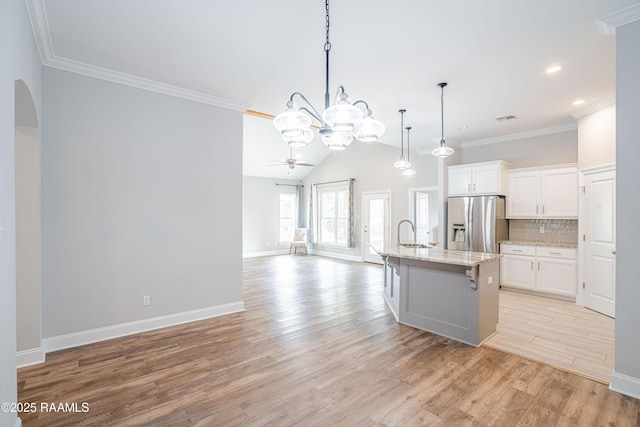 kitchen with white cabinetry, stainless steel refrigerator with ice dispenser, sink, and a center island with sink