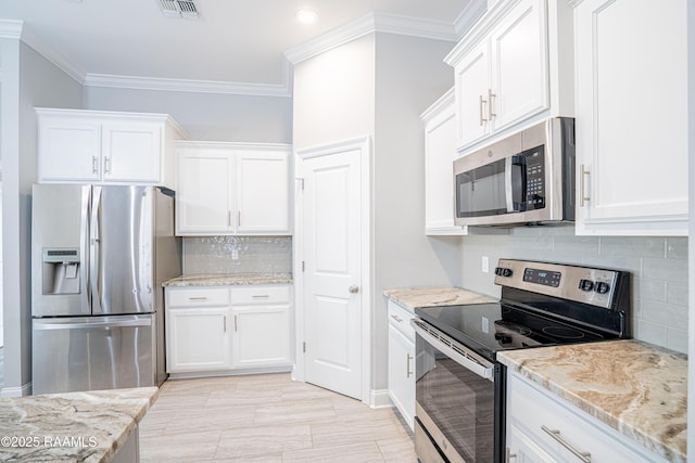 kitchen with light stone counters, appliances with stainless steel finishes, crown molding, and white cabinets