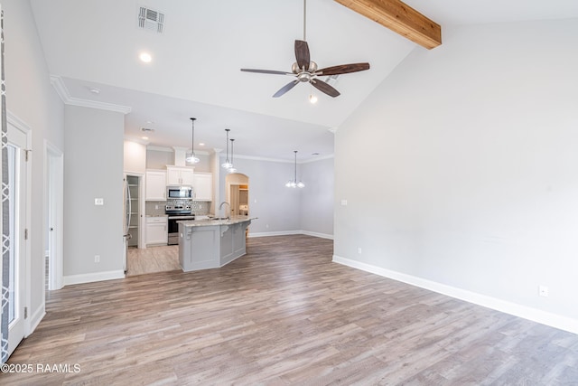 unfurnished living room featuring ceiling fan with notable chandelier, vaulted ceiling with beams, sink, crown molding, and light wood-type flooring