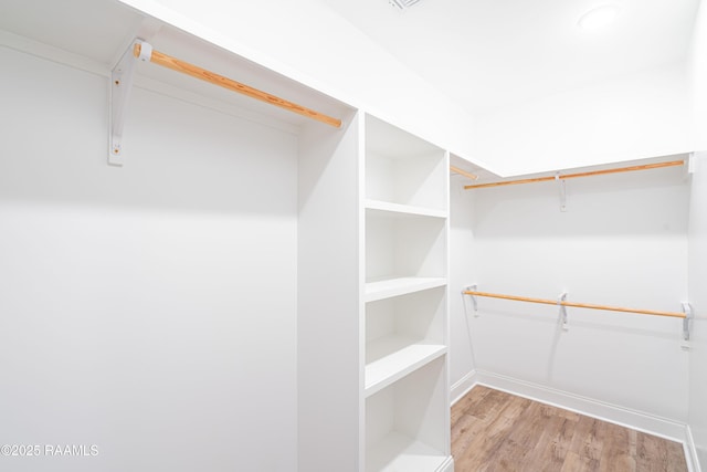 walk in closet with light hardwood / wood-style floors