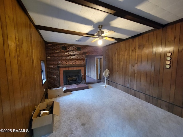 unfurnished living room with beam ceiling, carpet floors, and wooden walls