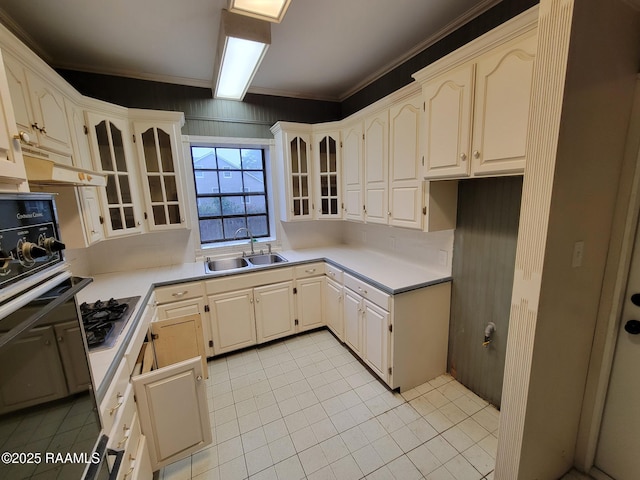 kitchen featuring sink, crown molding, light tile patterned floors, stainless steel gas stovetop, and oven