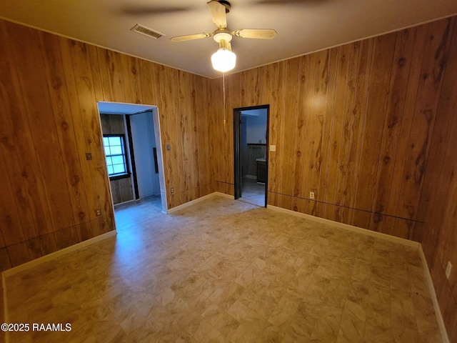 unfurnished room featuring ceiling fan and wooden walls