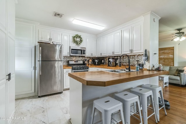 kitchen featuring wooden counters, stainless steel appliances, sink, and white cabinets