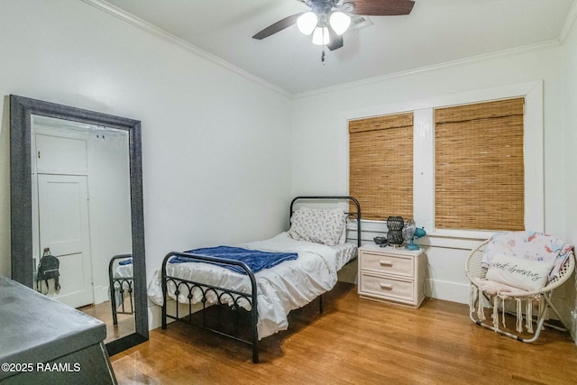 bedroom featuring hardwood / wood-style flooring, ornamental molding, and ceiling fan