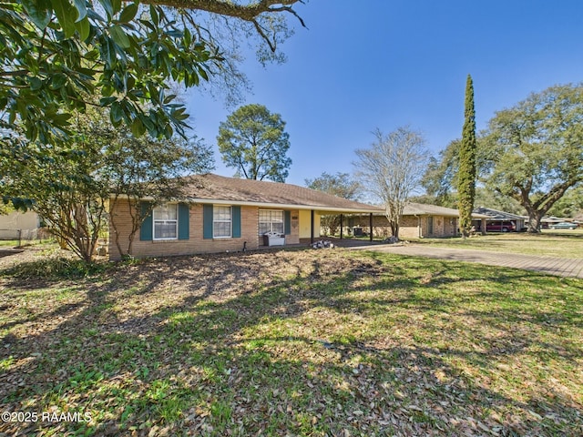 single story home with brick siding, a front yard, and an attached carport