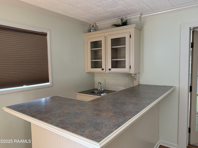 interior space with sink, crown molding, white cabinetry, backsplash, and kitchen peninsula