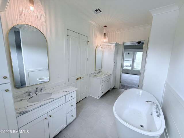 bathroom featuring a freestanding tub, two vanities, visible vents, and a sink