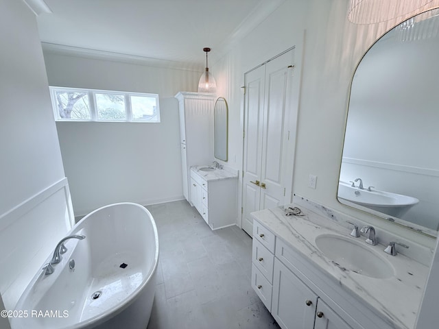 bathroom with two vanities, tile patterned floors, a freestanding tub, and a sink