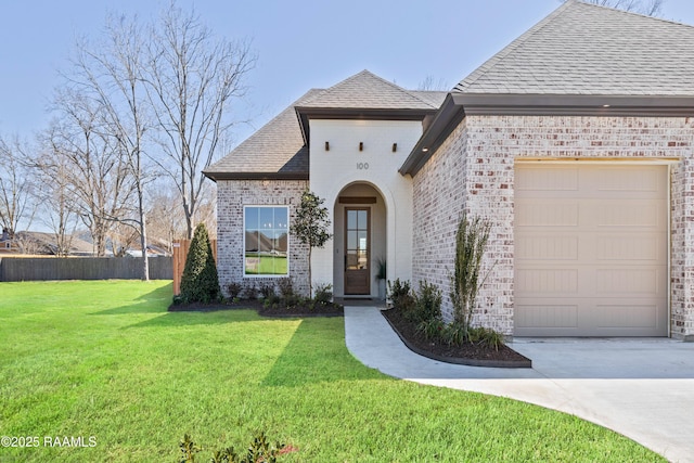 french provincial home with brick siding, roof with shingles, an attached garage, a front yard, and fence